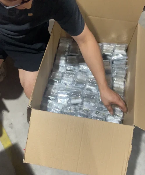 Warehouse supervisor placing completed sewing kits into standard shipping cartons