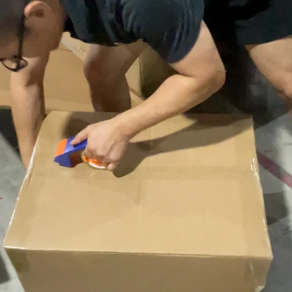 Warehouse worker sealing export cartons after final packing